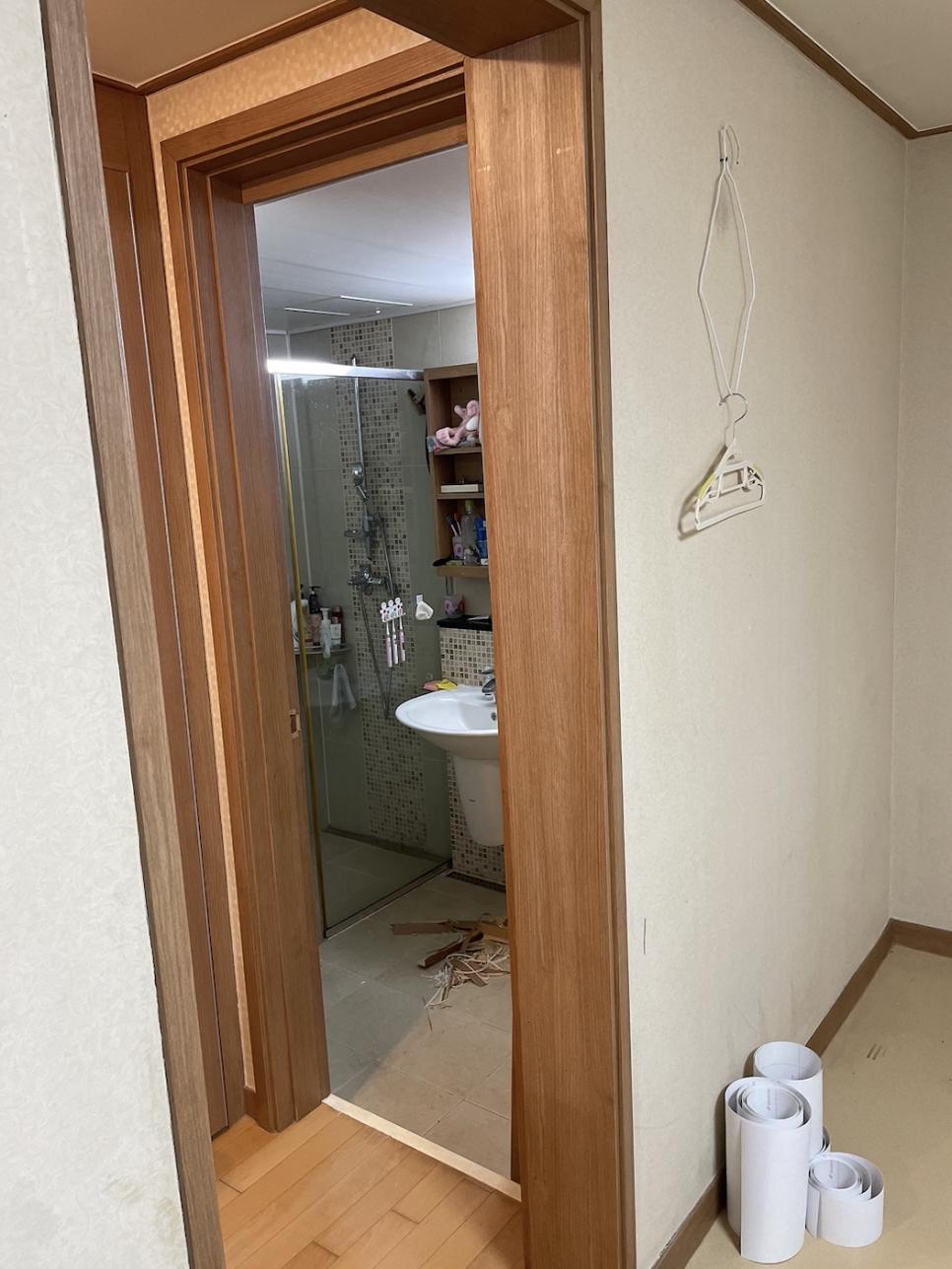 나무색 문틀이 보이는 욕실 내부 작업 준비 과정