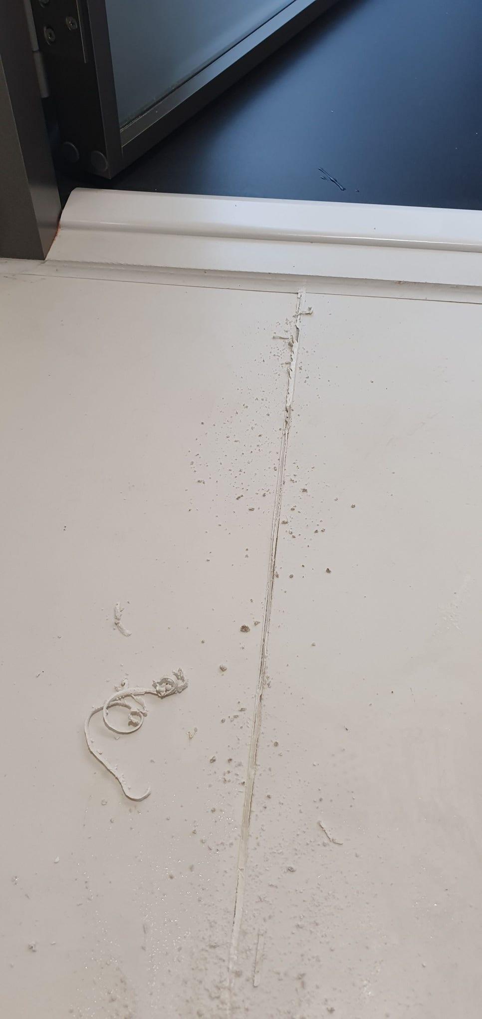 흰색 벽면 중앙의 틈과 흰색 잔해물이 보이는 공간