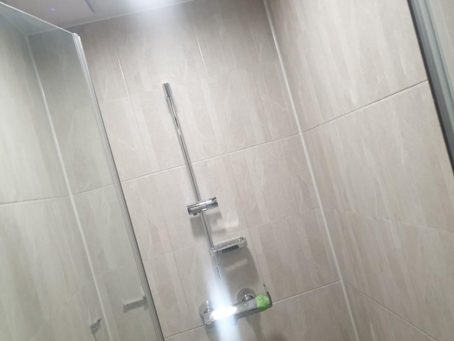 수전과 타일 라인이 매끄럽게 연결된 욕실 벽면