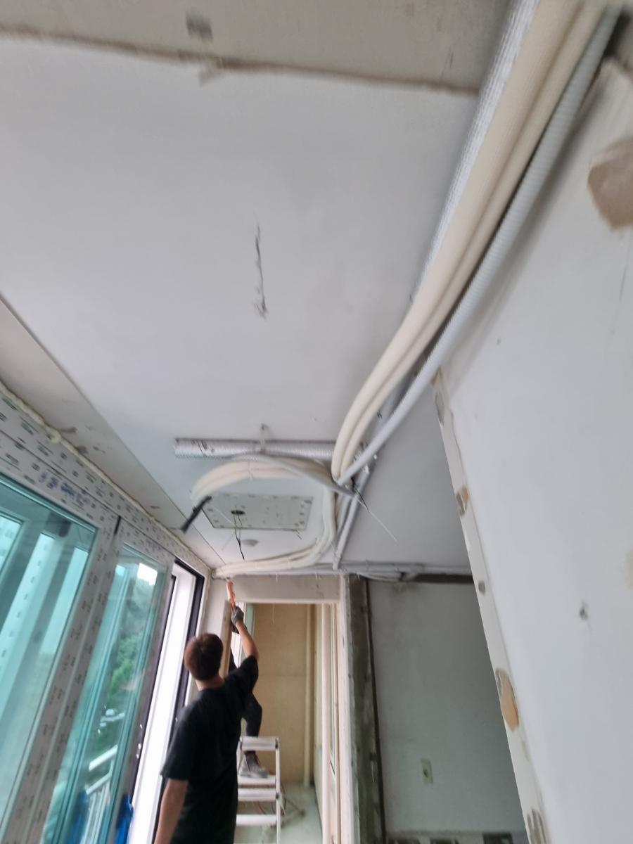 창문 근처 천장에 노출된 배관과 전선 작업 현장