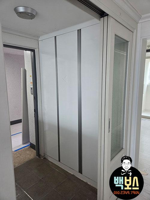 흰색 슬라이딩 도어와 유리 패널 수납장이 있는 복도
