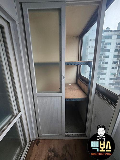 철제 선반과 흰색 슬라이딩 도어가 있는 발코니
