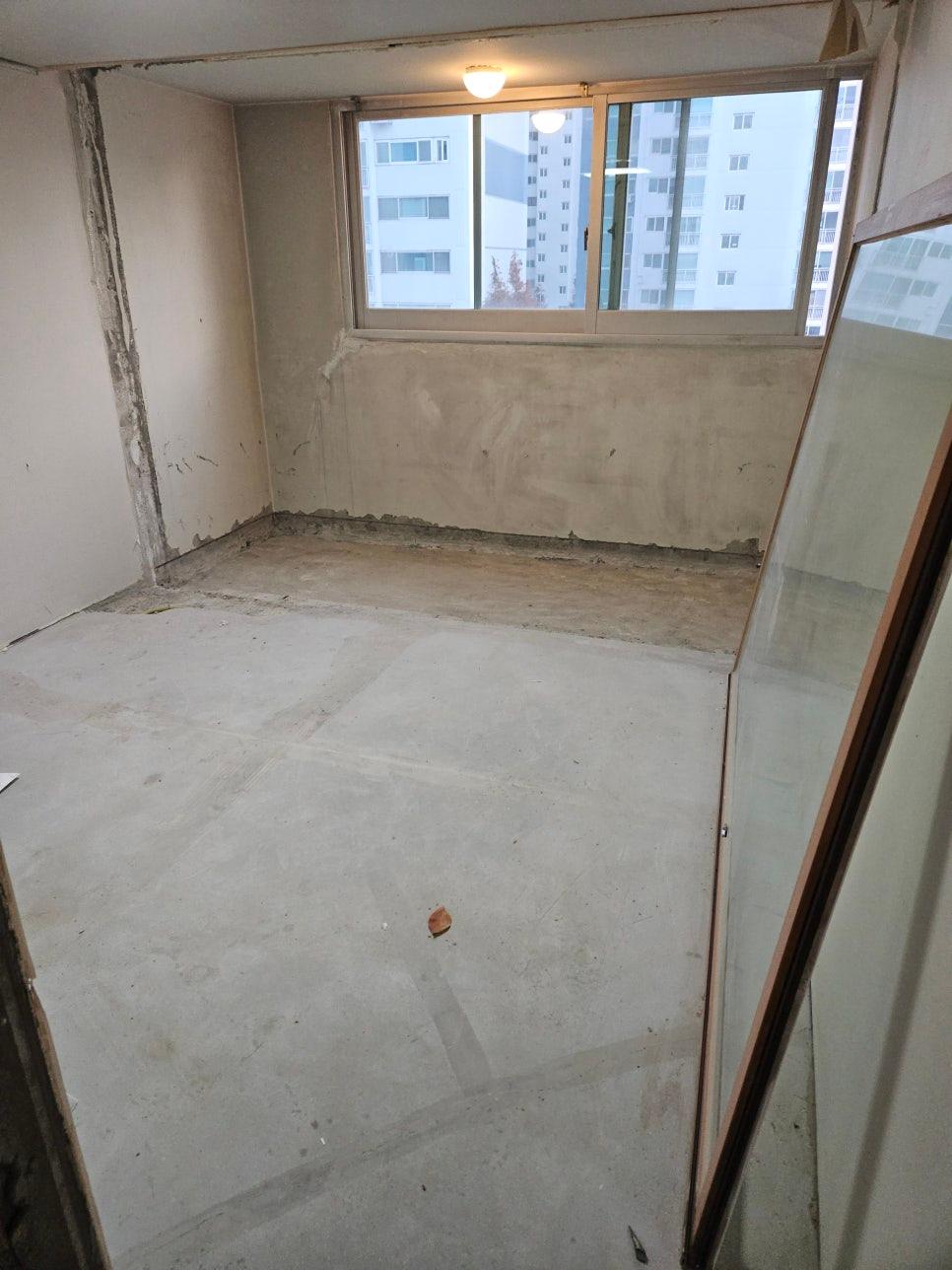 콘크리트 벽과 바닥, 창호가 있는 방의 공사 모습입니다