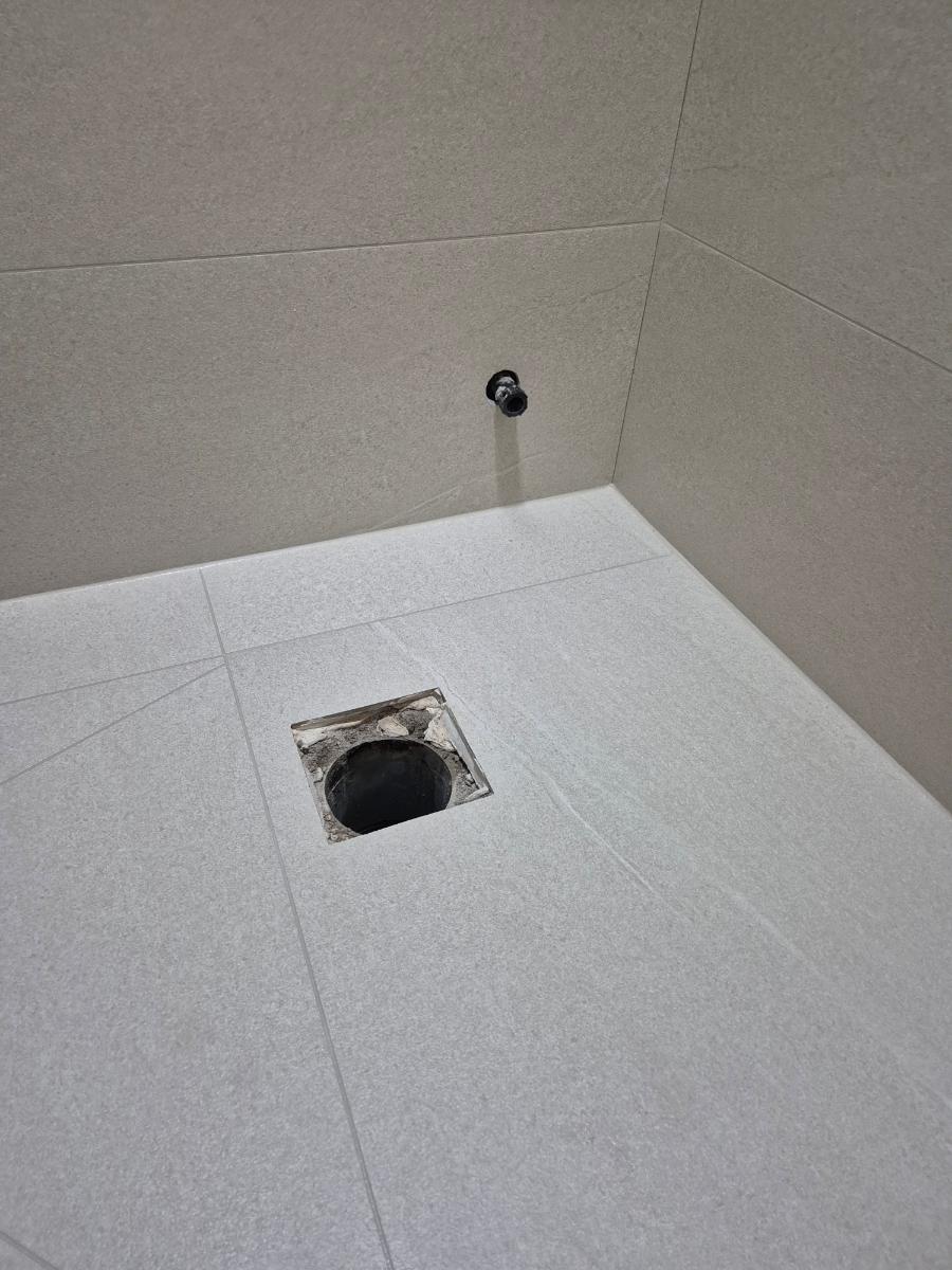 흰색 타일 바닥의 배수구와 수도관 연결부 작업