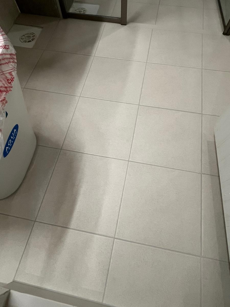 배수구와 유리문이 보이는 흰색 타일 바닥