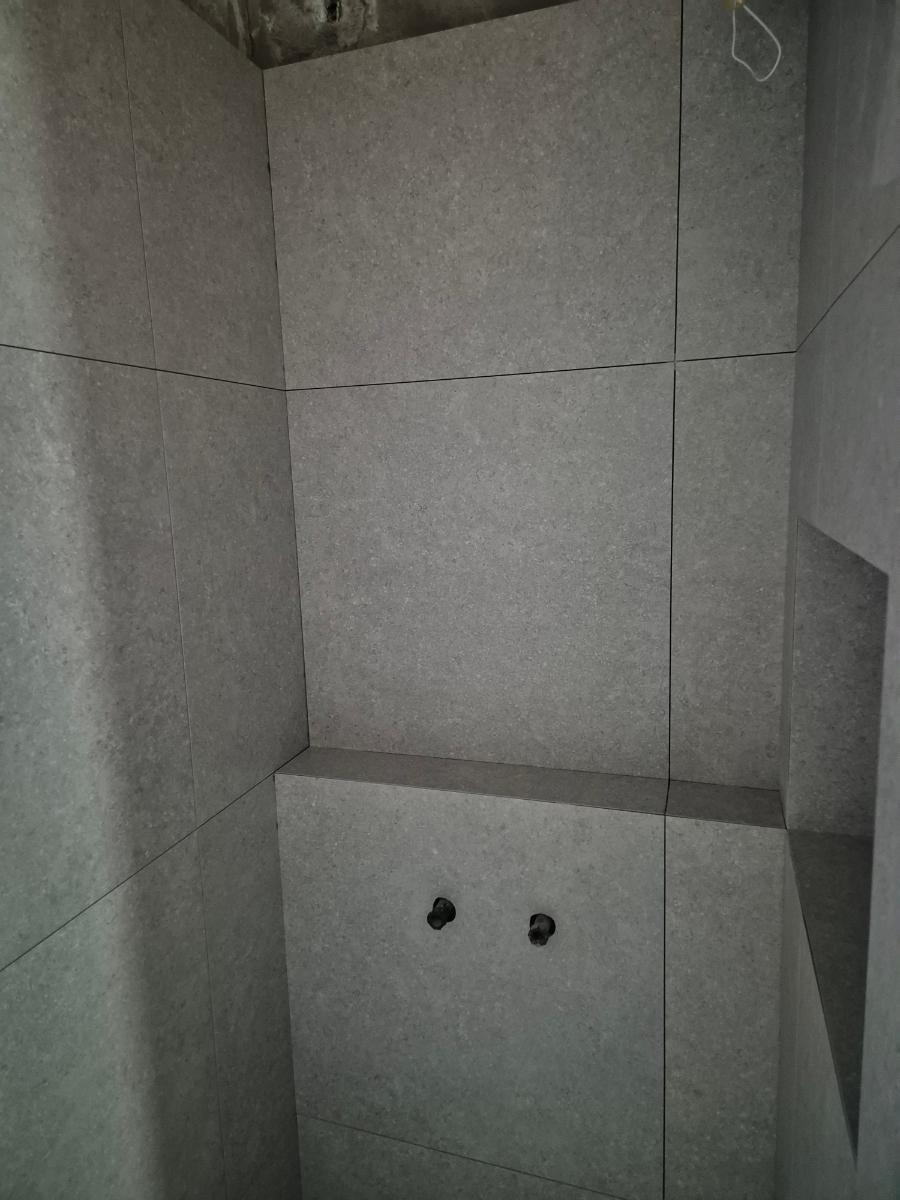 배수구가 위치한 회색 타일 벽면의 모습