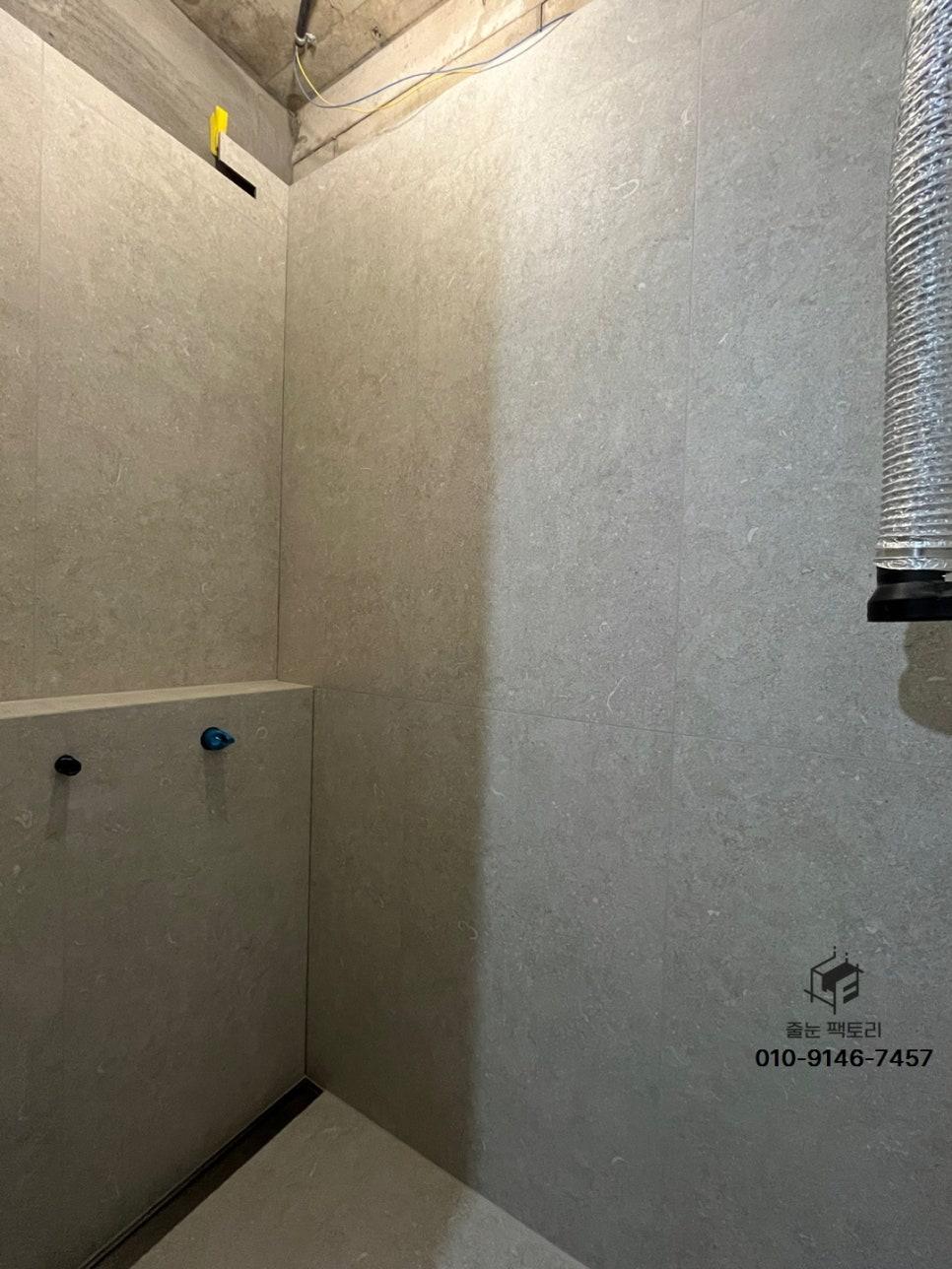 회색 타일 벽면과 노출 배관이 보이는 천장
