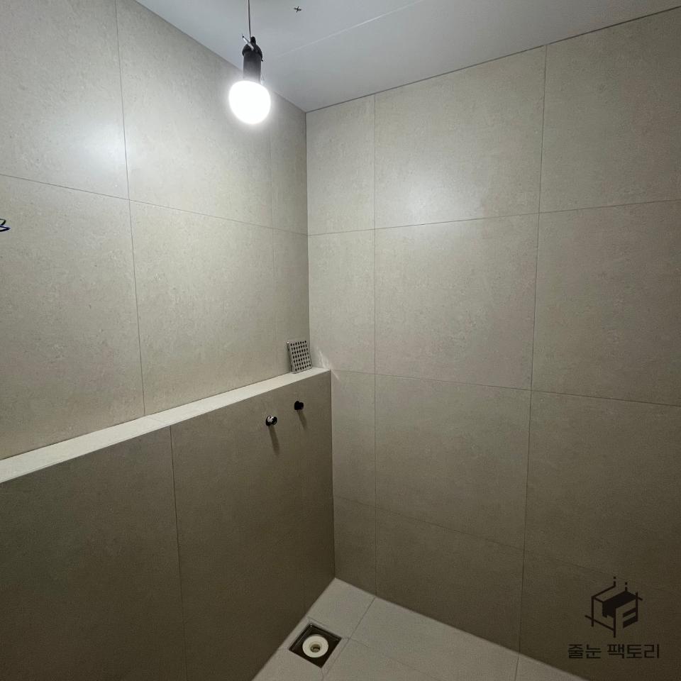 샤워 설비와 줄눈이 보이는 벽 타일 장면