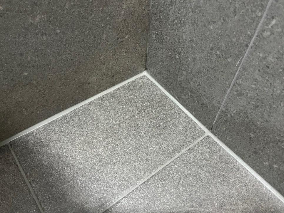 회색 타일 모서리의 흰색 실리콘 접합제 마감