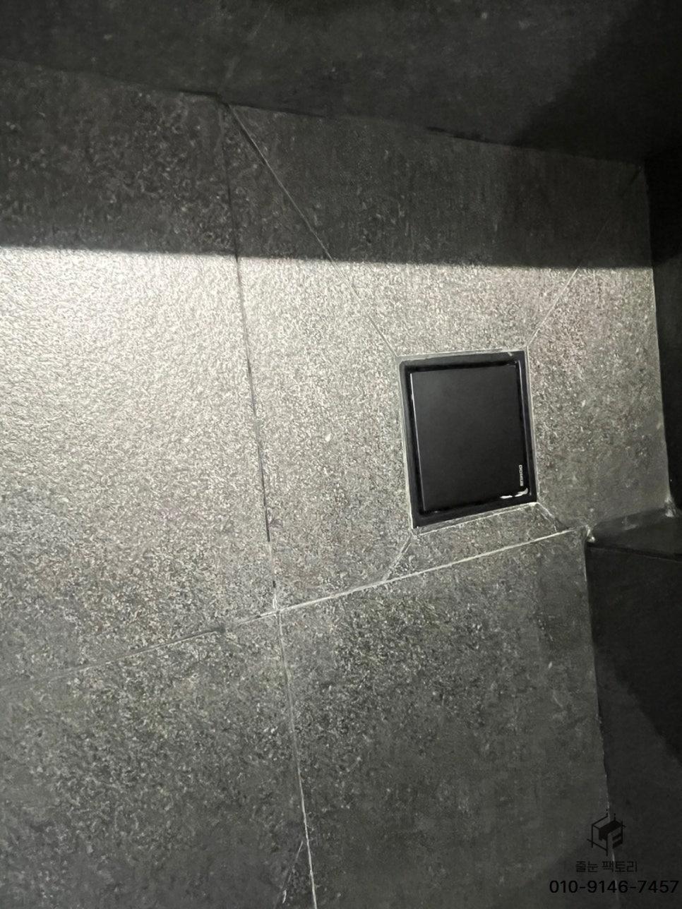 벽면 타일에 설치된 검은색 정사각형 장치