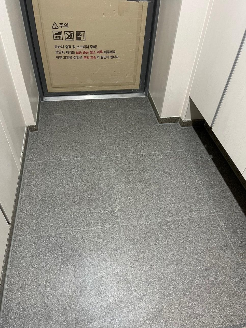 흰색 벽면과 문이 보이는 복도 타일 바닥