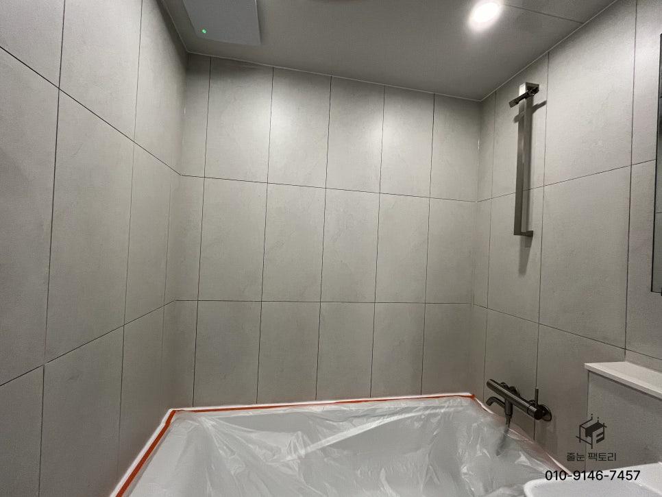 보호막으로 덮인 욕조와 회색 타일 벽면