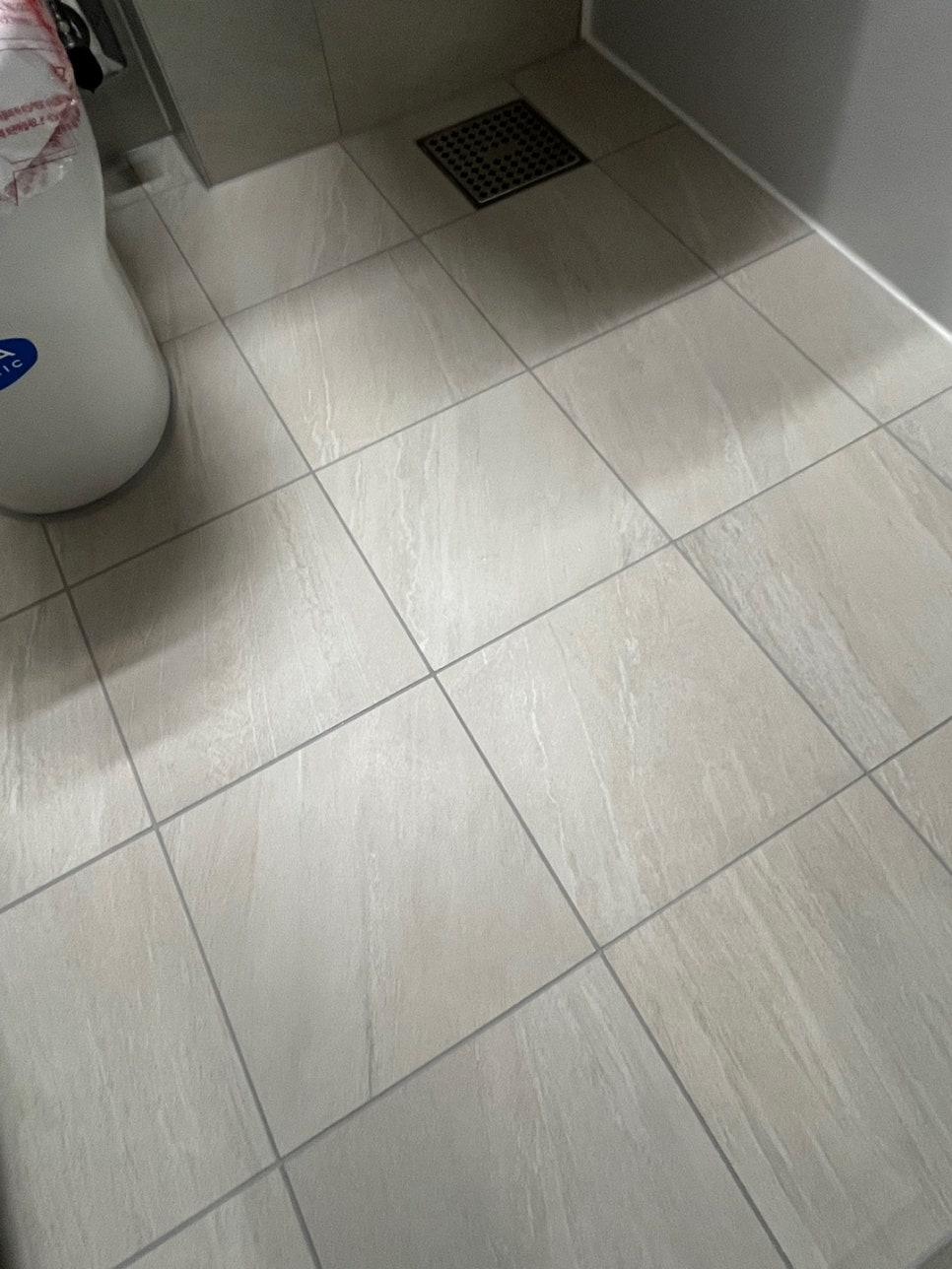 흰색 욕조 일부와 검은색 배수구가 보이는 바닥