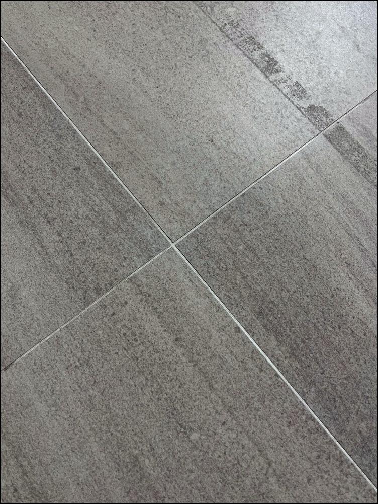 회색 타일 표면과 흰색 실리콘 틈새 근접샷