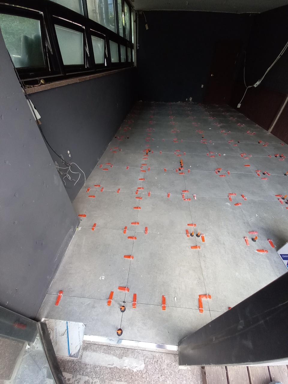 빨간색 평탄클립으로 타일 단차를 조정하는 상태