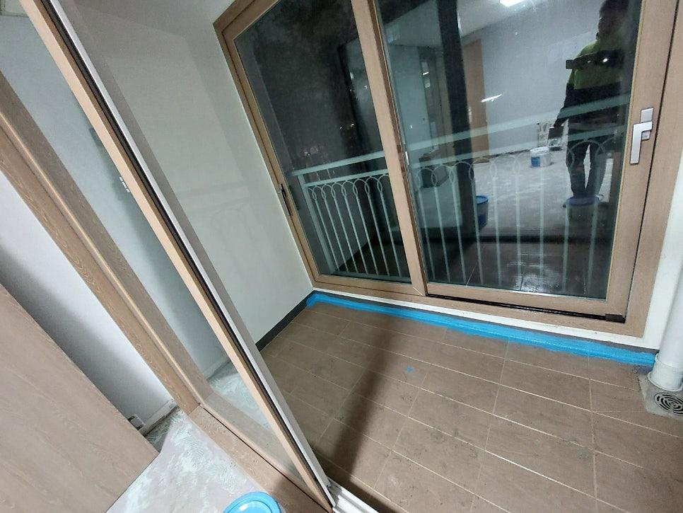 슬라이딩 도어와 파란 테두리가 보이는 발코니 바닥 작업 현장