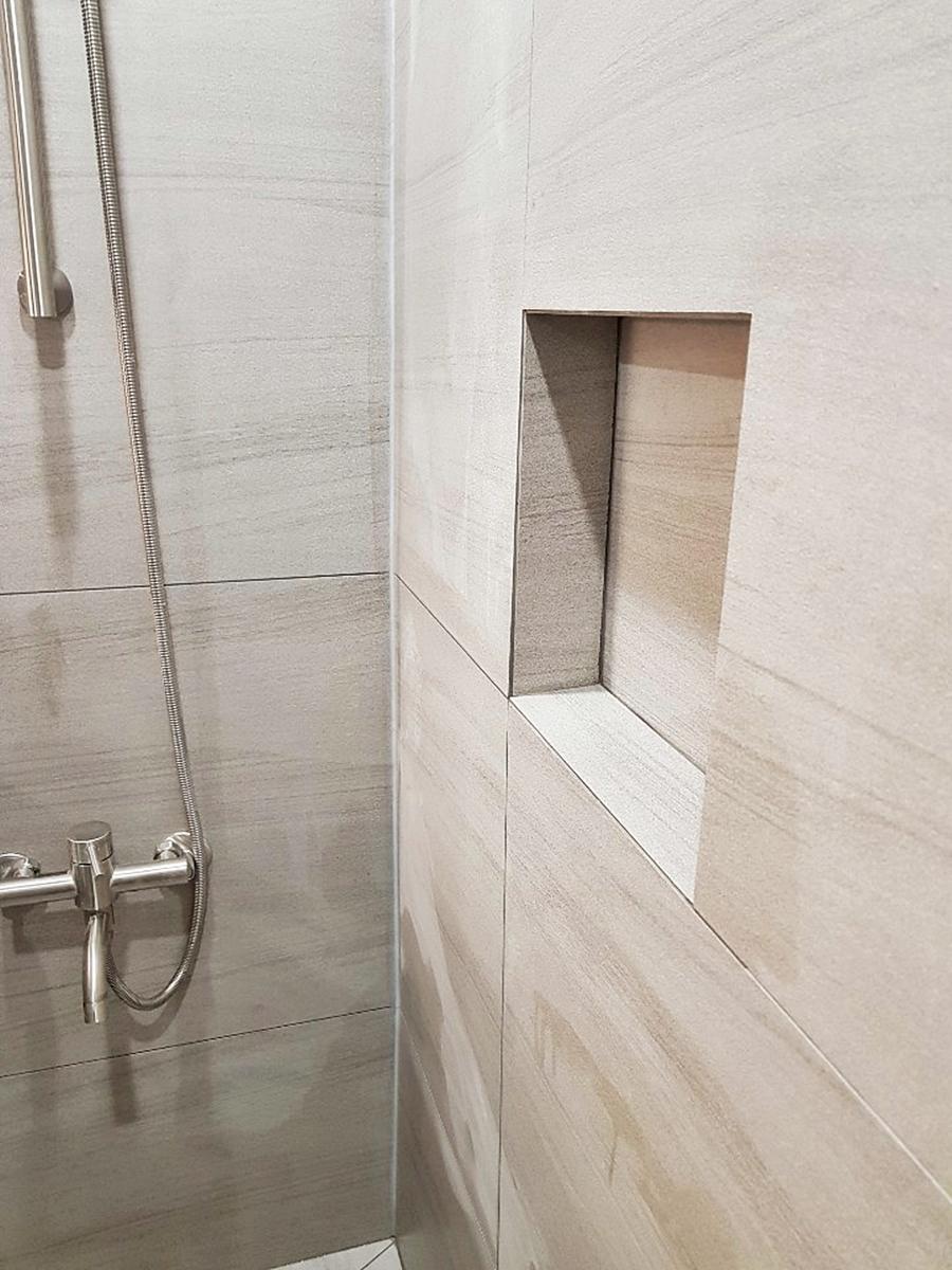 샤워실 벽면의 타일 수납공간과 수전