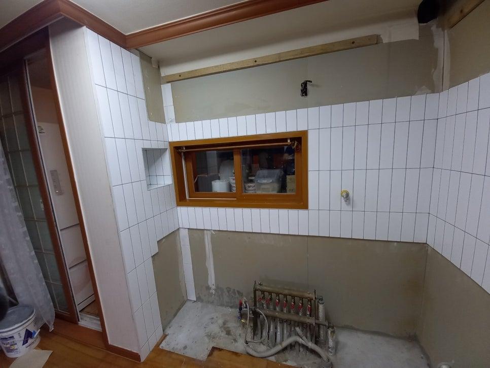 수도꼭지와 배수관이 설치된 타일 벽면과 유리문