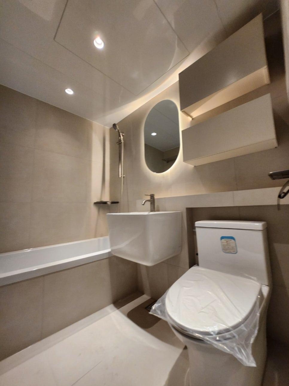 차분한 회색 톤의 타일과 원형 거울 배치