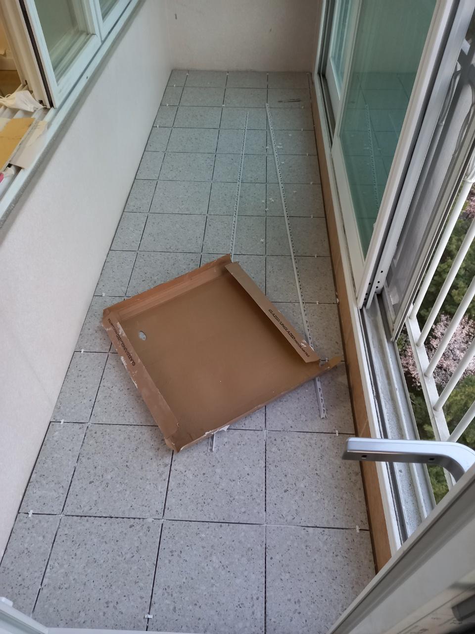 바닥 타일 시공 중인 발코니와 슬라이딩 창호