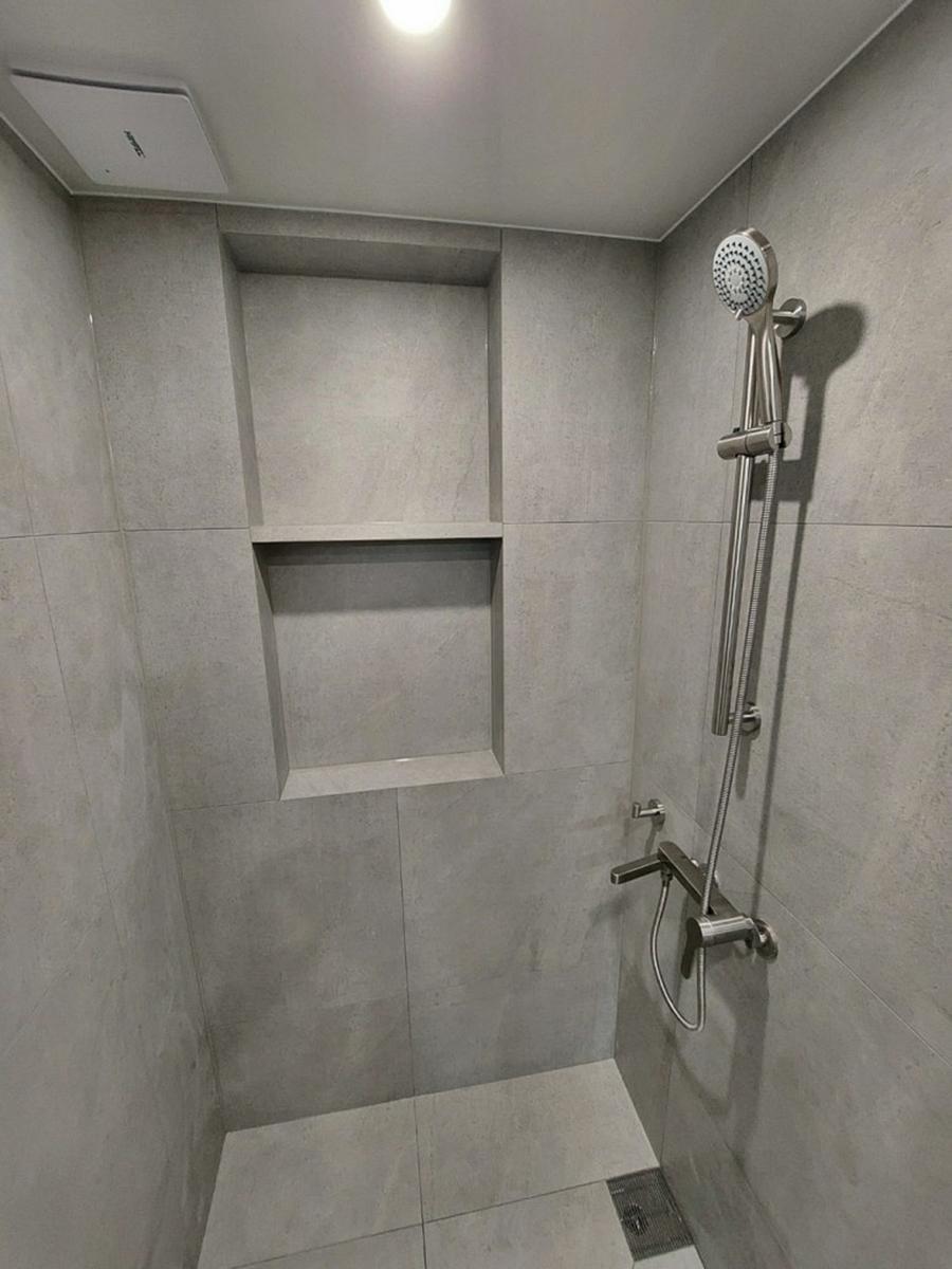 줄눈이 보이는 벽 타일과 샤워 설비