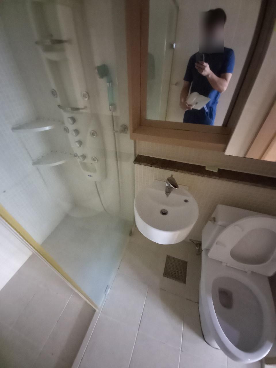 거울과 세면대 주변의 타일 상태를 점검하는 장면
