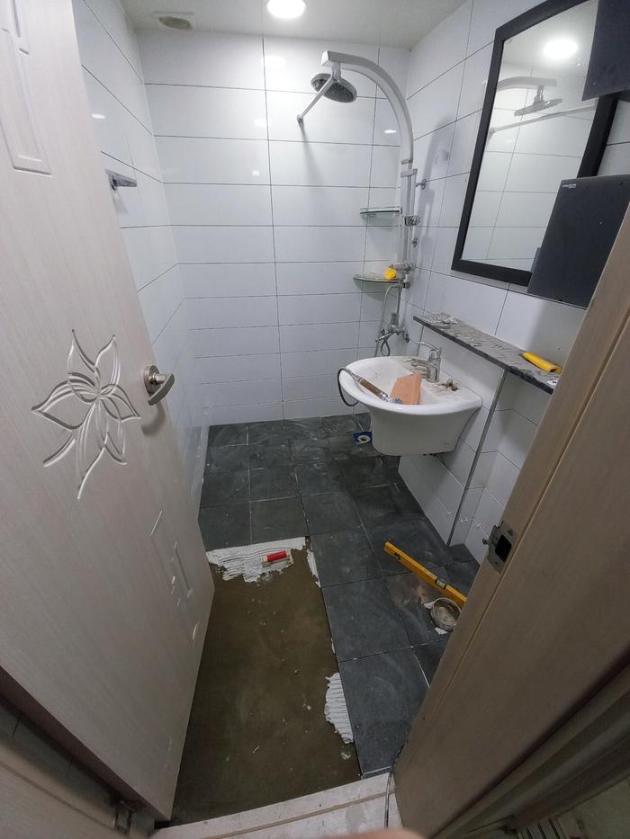 거울과 세면대 주변의 타일 마감 작업 장면