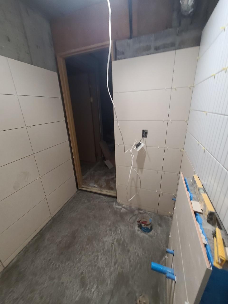 전선이 노출된 상태로 타일 작업 중인 벽면