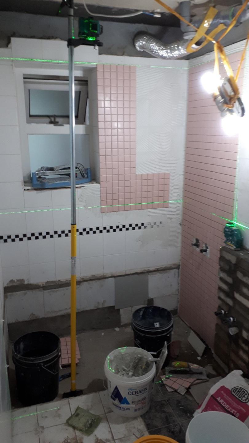 핑크색 타일을 벽면에 부착하는 시공 과정