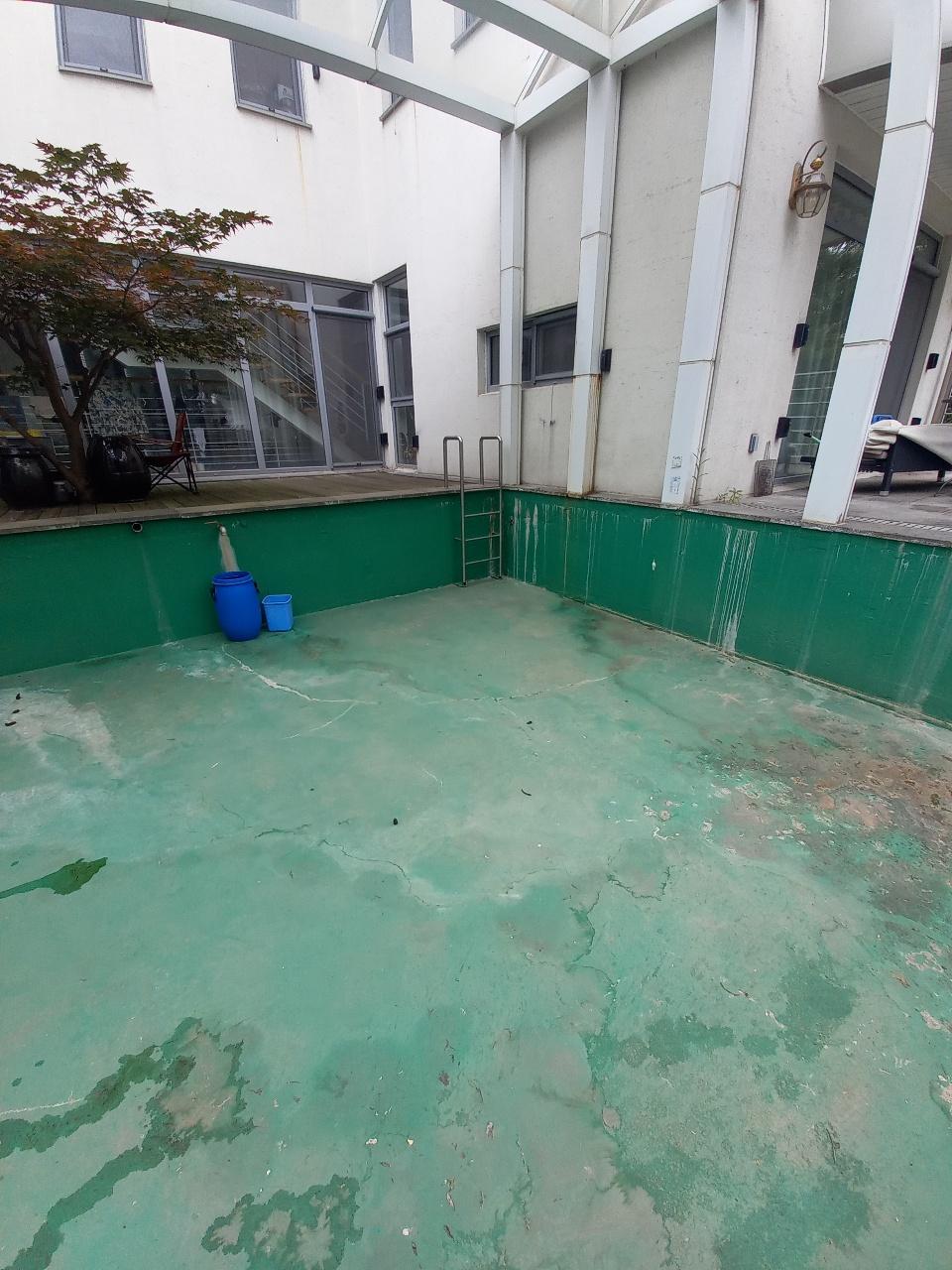녹색 벽면과 바닥이 보이는 시공 전 수영장 공간