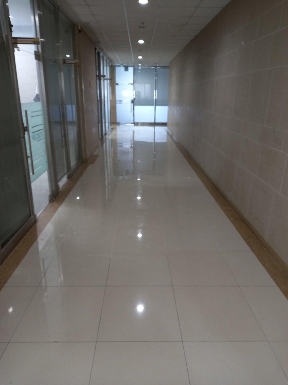 흰색 타일 바닥과 벽돌 벽이 마주한 복도 공간