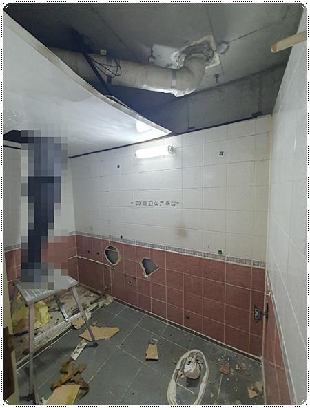 타일 벽면과 천장 배관, 바닥 철거물이 놓인 현장