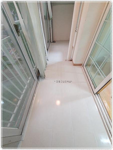 베이지색 벽면과 흰색 타일 바닥의 복도 전경