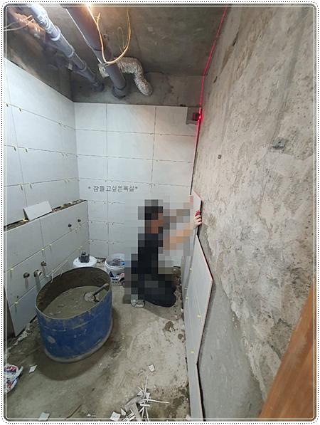 천장 배관이 노출된 상태에서 타일 작업이 진행 중인 모습