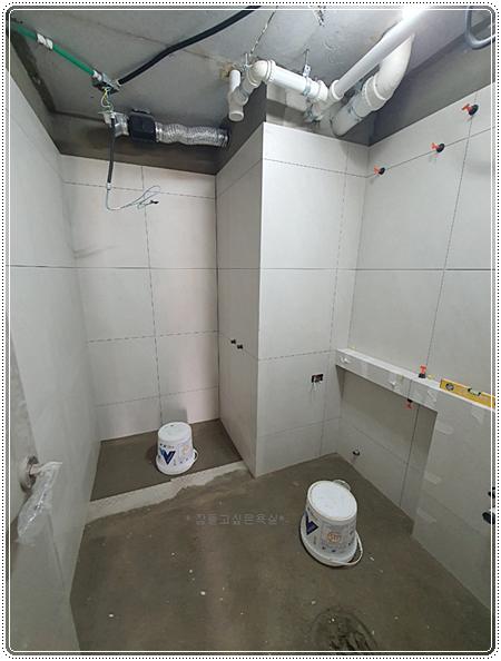 흰색 타일을 벽면에 부착하는 떠발이 시공 과정