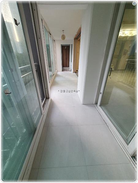 흰색 타일 바닥과 슬라이딩 창호가 보이는 복도