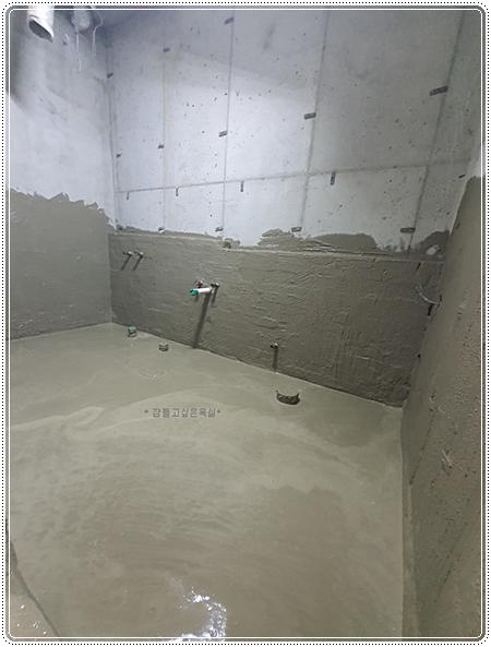 콘크리트 마감 상태의 벽면에 설치된 수전과 배관