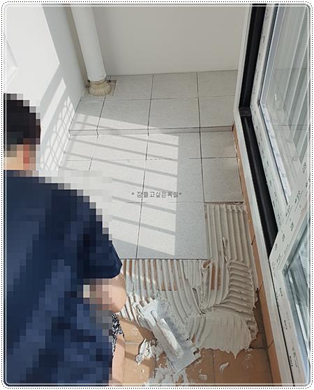 발코니 바닥에 그레이 톤 타일이 시공 중인 모습