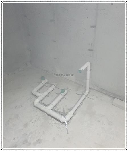 벽과 바닥에 설치된 흰색 PVC 배관과 녹색 커넥터