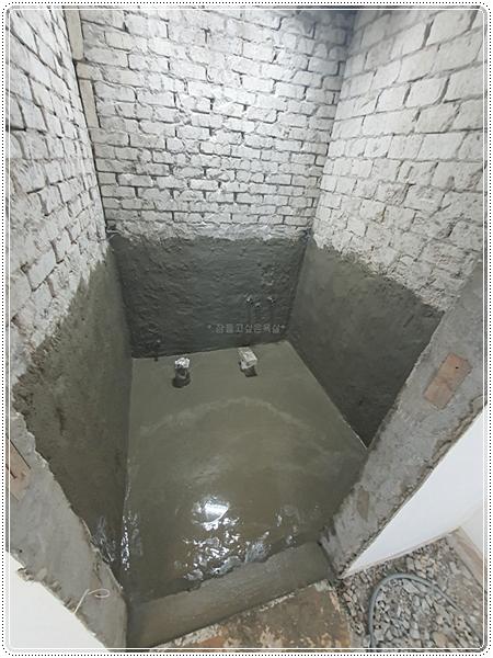 벽돌 벽과 물이 고인 바닥이 보이는 설비 공사 과정