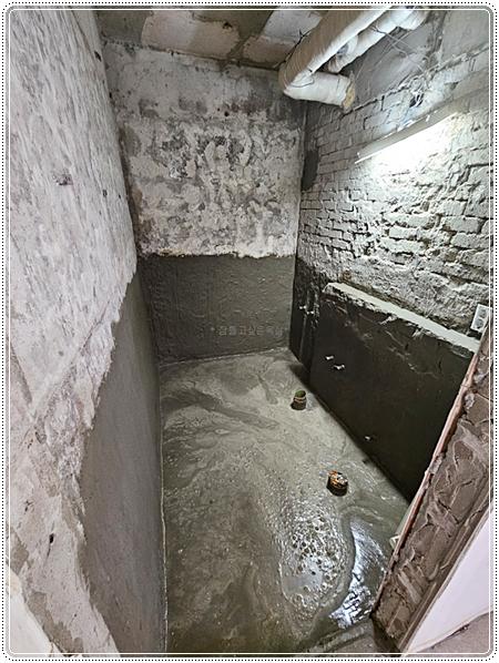 콘크리트 벽면과 바닥에 물이 고여 있는 철거 현장