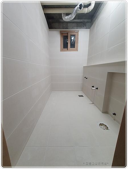 흰색 타일로 마감된 벽과 바닥 및 천장 배관