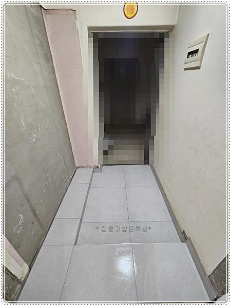 바닥 타일 마감 후 벽면이 노출된 복도 공간