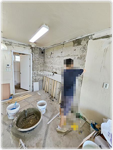 콘크리트 벽면이 노출된 주방 철거 현장과 시멘트 믹싱통
