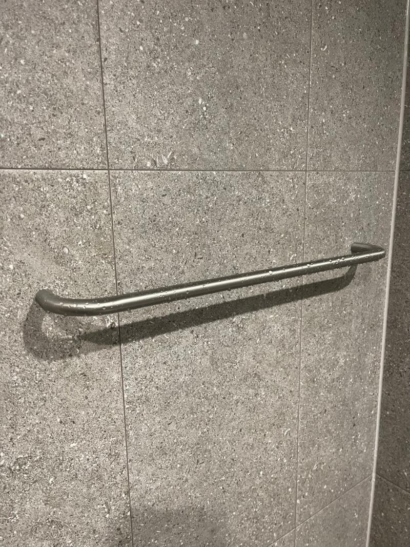 그레이 톤 석재 타일로 마감된 벽면과 금속 손잡이