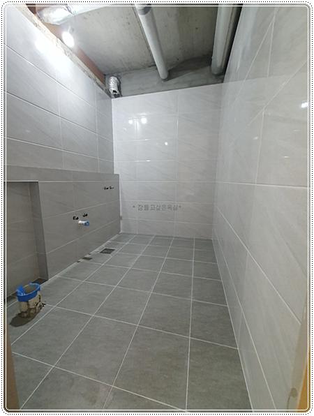 벽 타일 시공 전 샤워 설비와 줄눈이 보이는 벽면
