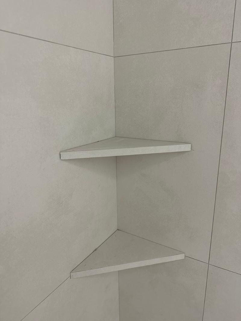 회색 타일 벽면에 부착된 삼각형 코너 선반