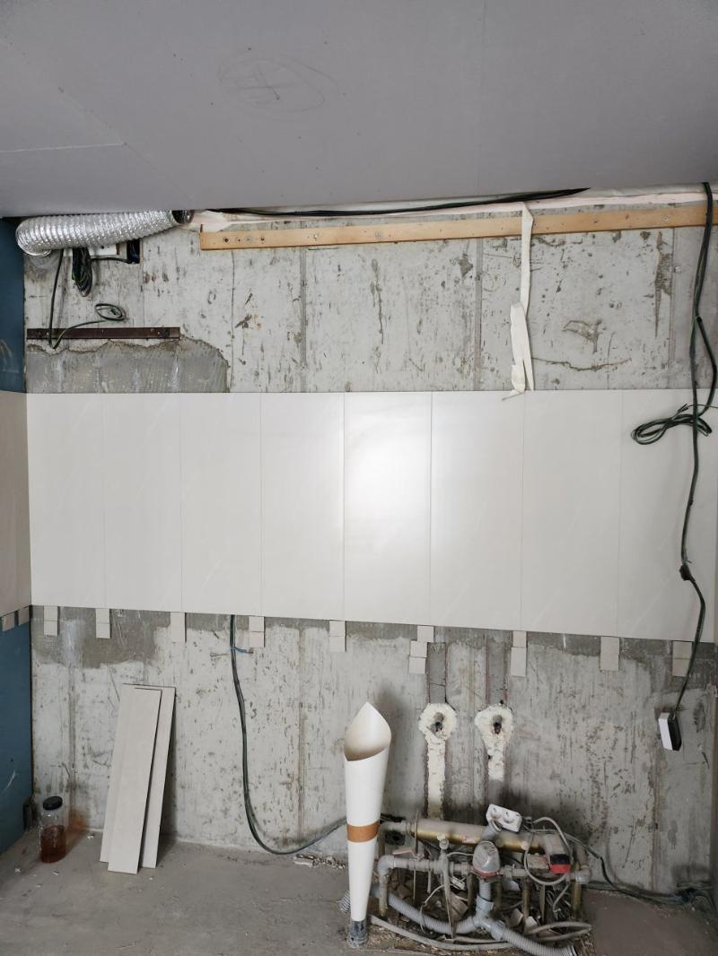 콘크리트 벽면에 흰색 타일이 부분적으로 부착된 상태