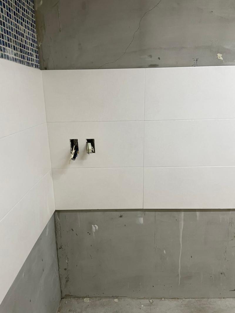 전기 박스가 노출된 흰색 타일 벽면과 콘크리트 벽