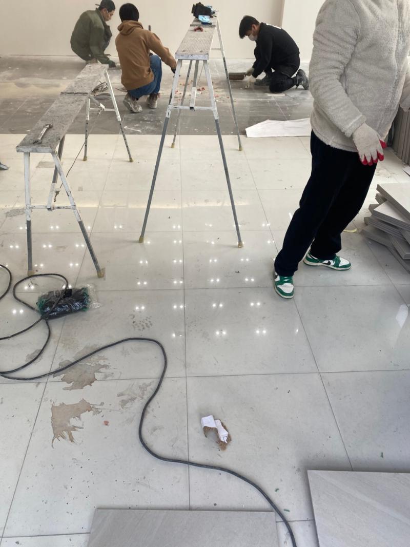 작업자들이 타일 바닥을 시공 중인 내부 전경